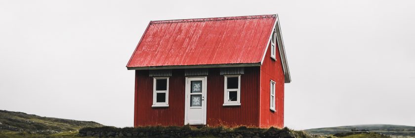 A small red house sits on a quiet hill.