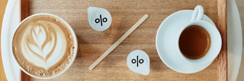 wooden tray with a cup of espresso and a cappuccino with creamers in the shape of percentage sign