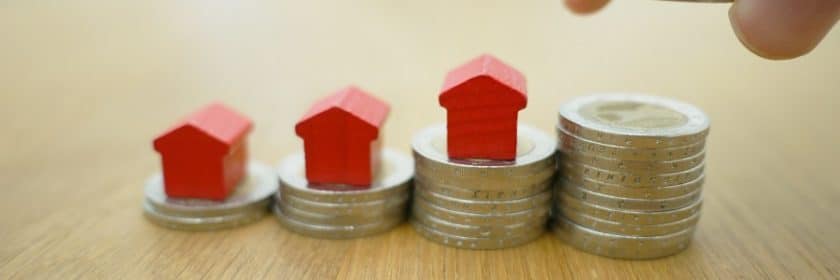 Small toy houses sit atop stacks of coins