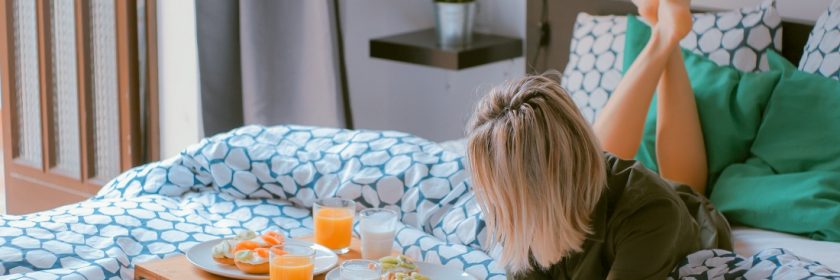 Blonde woman has breakfast in bed in a clean, modern bedroom