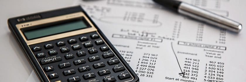 calculator next to pen and financial information