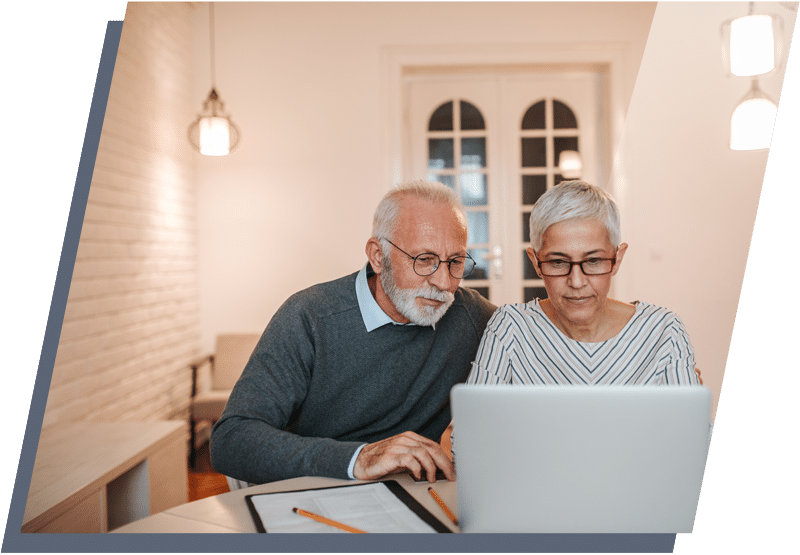 Older man and woman sitting next to each other and looking at a laptop