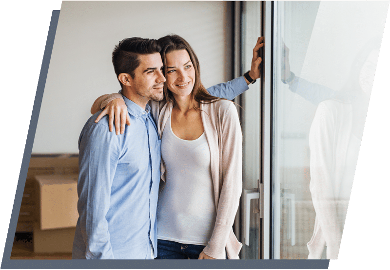 Man and woman standing next to each other smiling while looking out a glass door