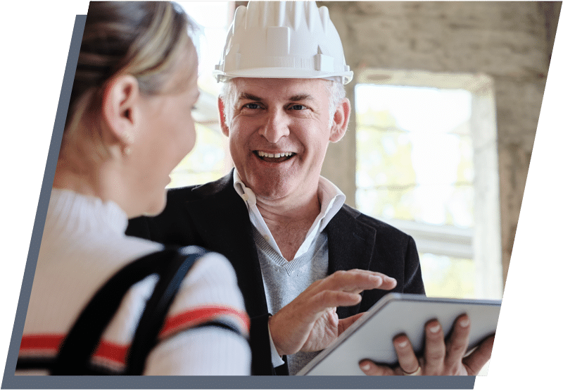 Male construction worker wearing a hardhat speaking with a woman