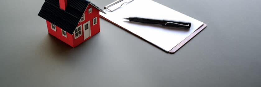 House figurine next to pen and paper