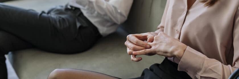 Man and woman sitting on couch taking off wedding rings