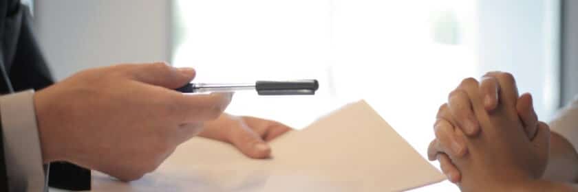 person holding paper handing over a pen