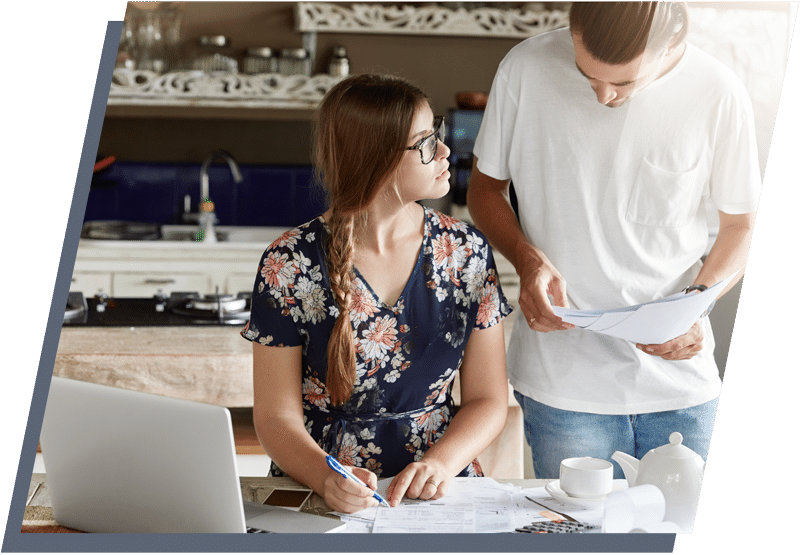 Young couple reviewing documents with a laptop and calculator