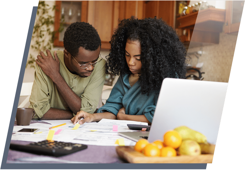 Young couple sitting at a kitchen table looking over financial statements