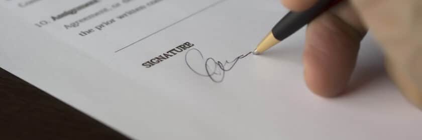 Hand holding a pen signing a document