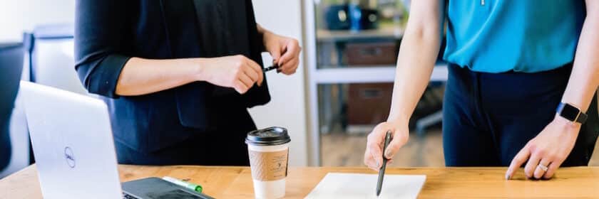 Two women in discussion with one pointing a pen at a piece of paper