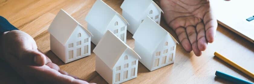nvestment concepts with investor and white model house on desk background.