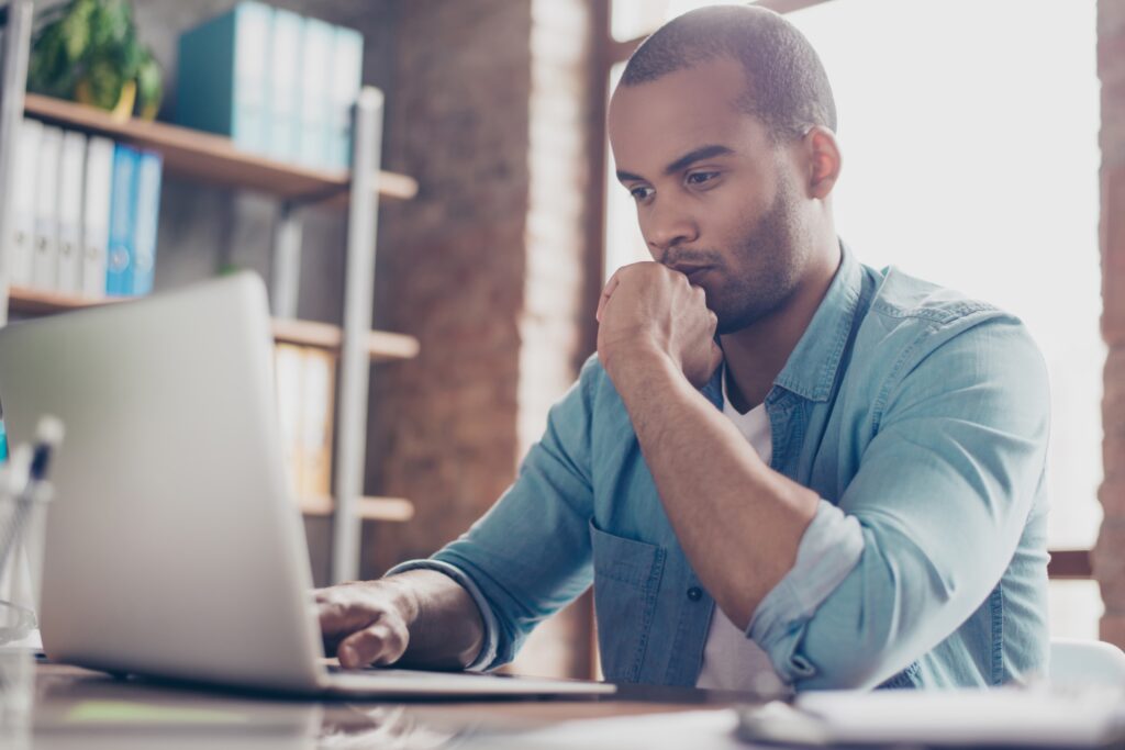 Skeptic young freelancer sitting and analyzing data in the computer.